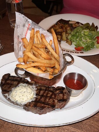 La Grande Boucherie signature dishes Steak Frites, Onion Soup Gratinée, Escargots de Bourgogne, Plateau de Fruits de Mer (Seafood Platter), Profiteroles.